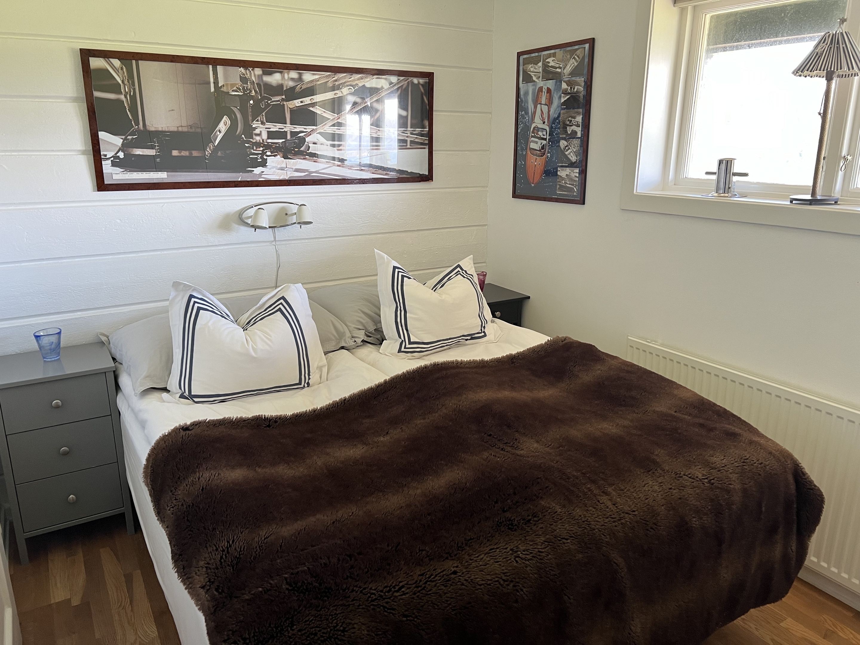 Contemporary hotel bedroom showcasing a comfortable bed with a neutral bedspread, wooden headboard, sleek nightstands, and a blue armchair by the window, creating a relaxing and inviting atmosphere